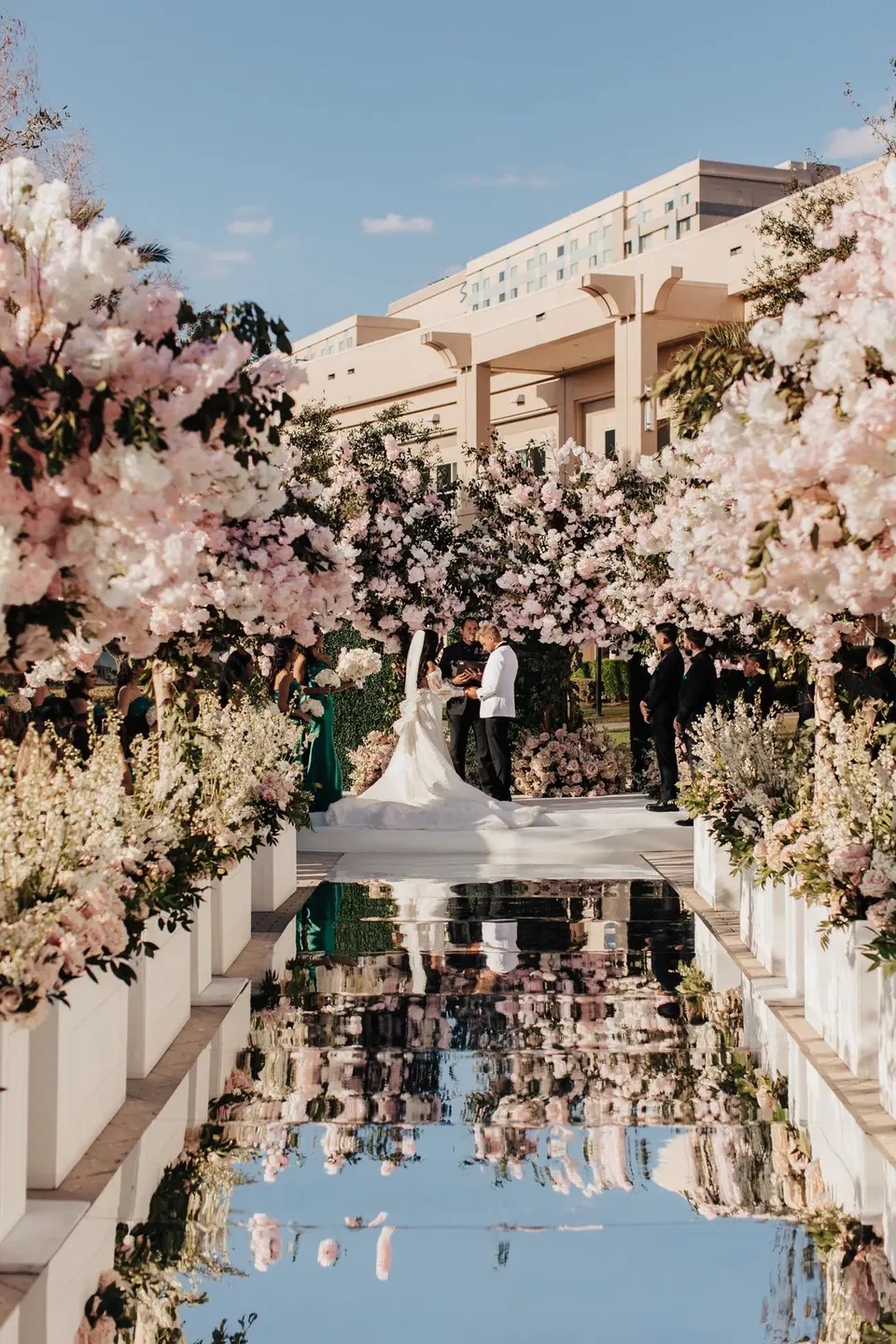 A grand floral ceremony and mirrored aisle beneath a blue sky