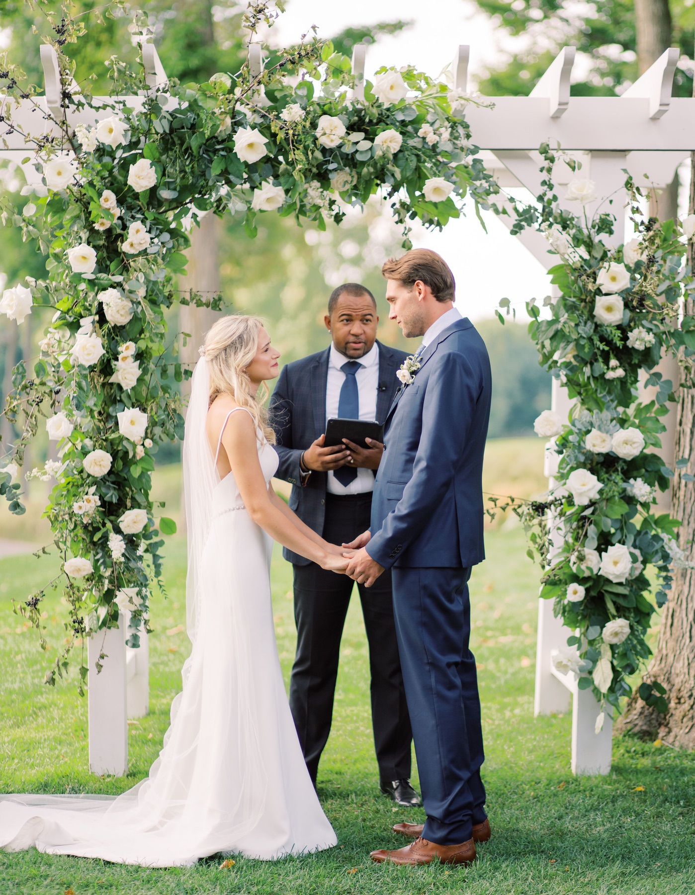 Wayde officiating a wedding beneath a floral arch