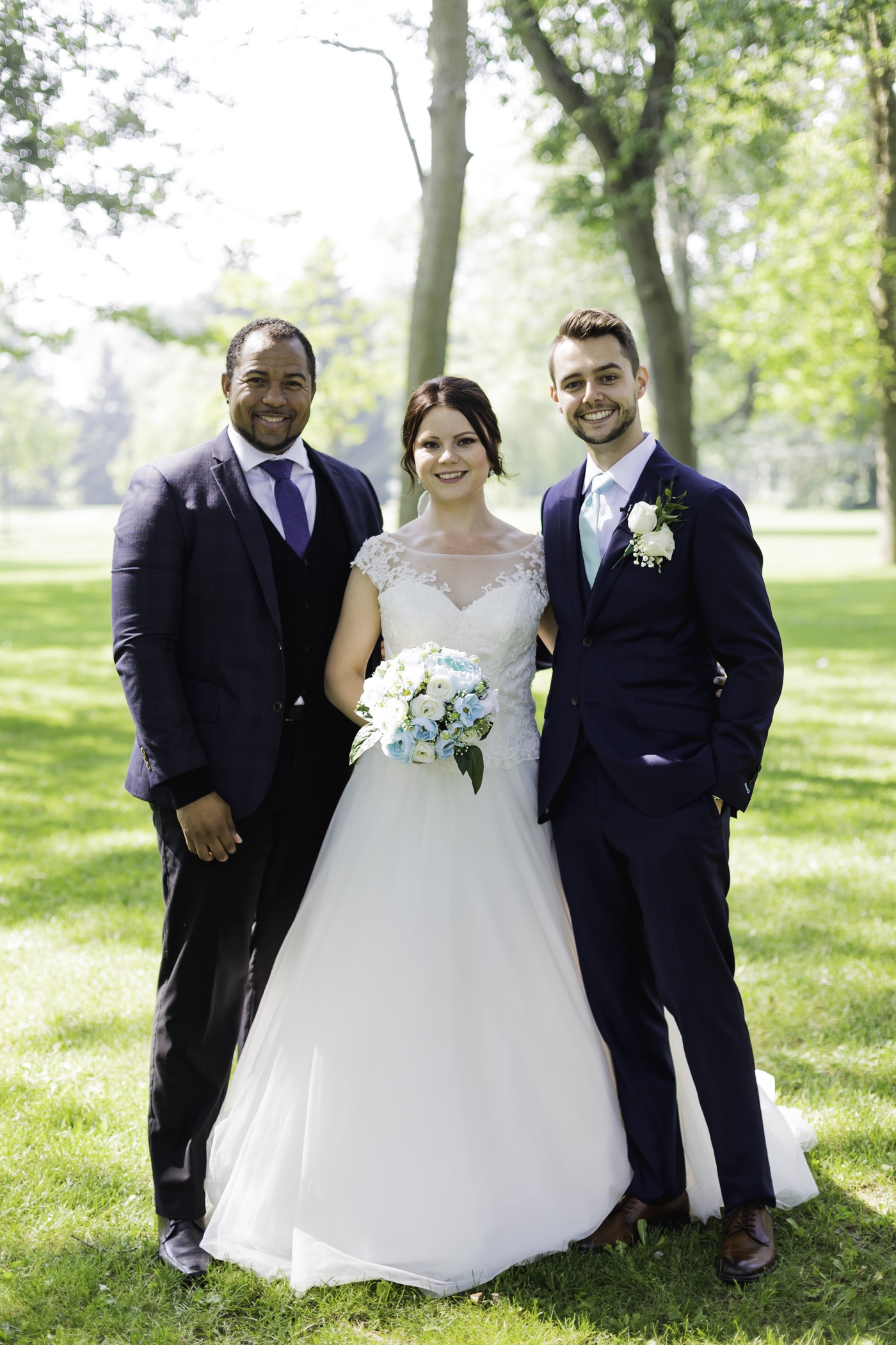 Wayde posing with newlyweds after their outdoor ceremony